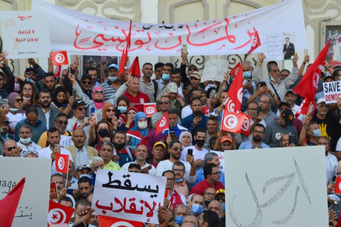 Demonstranter i Tunis holder tunisiskeflagg og plakater under en protest.