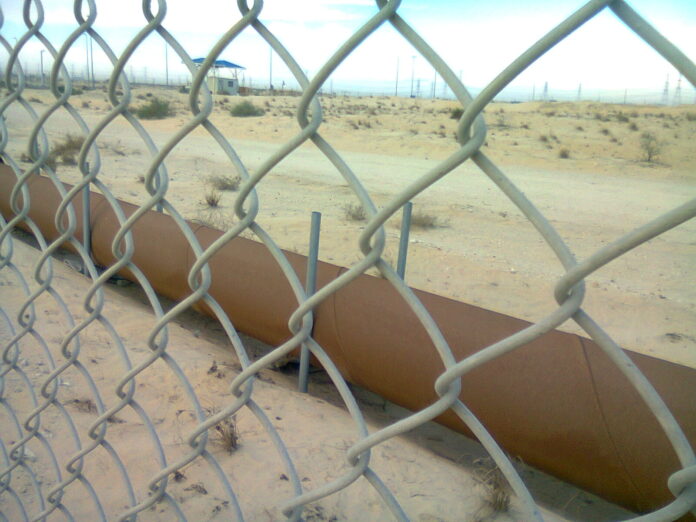 Oljerørledning bak gjerde i ørkenlandskap i Jubail i Saudi-Arabia.