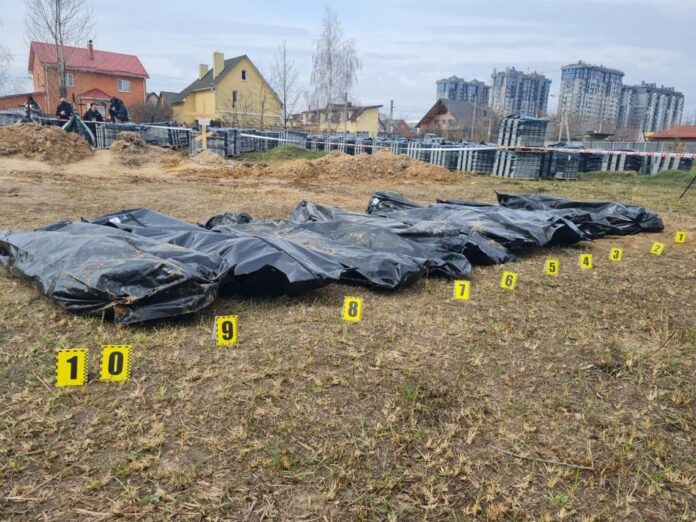 Likposer ligger på bakken ved en massegrav i Bucha under ukrainsk politis dokumentasjonsarbeid.