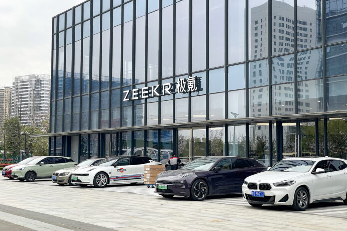 Biler står parkert foran et Zeekr-leveringssenter i en moderne bygning i Kina.