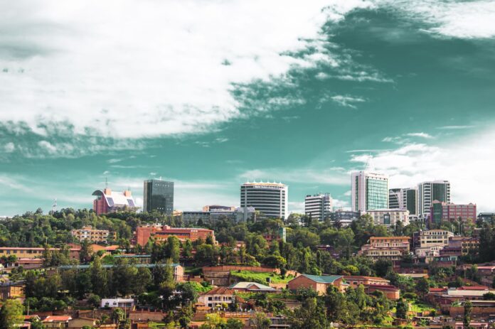 Panoramabilde av Kigali med grønne åssider, lav bebyggelse i forgrunnen og moderne høyhus i bakgrunnen.