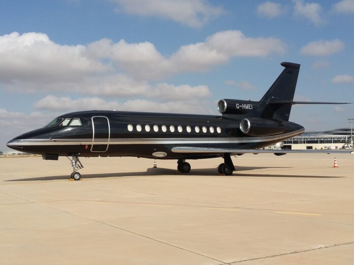 Svart privatfly av typen Dassault Falcon 900B parkert på en flyplass.