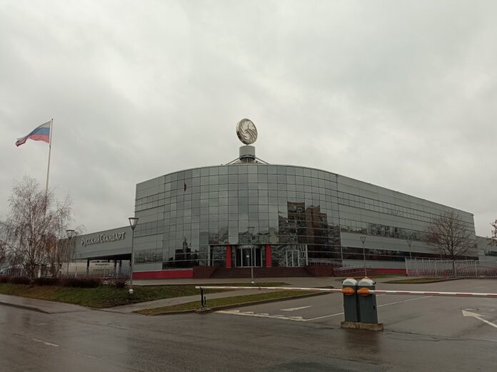 Utvendig bilde av en stor fabrikkbygning til Russian Standard i Moskva, med russisk flagg foran.