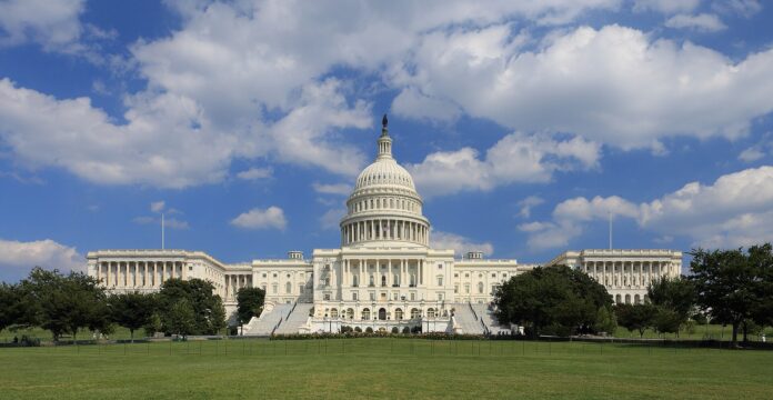 US Capitol sett fra vestsiden under blå himmel med skyer.