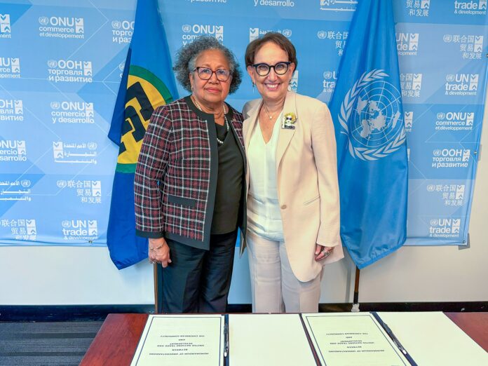 Rebeca Grynspan og Carla Barnett poserer foran UNCTAD-bakgrunn og flagg